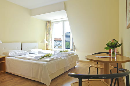white upholstered bed near table and chairs thumbnail