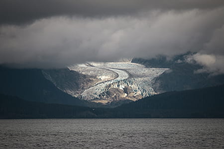 body of water near hills covered with trees at daytime thumbnail