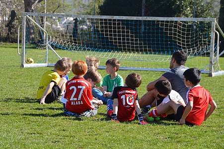 boys sitting on grass near soccer goal net thumbnail