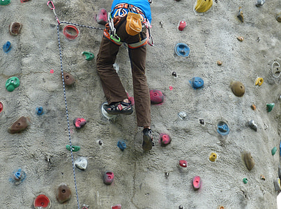 person in brown pants and pair of black hiking shoes doing wall climbing thumbnail