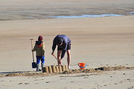 man and child making sand castles during daytime thumbnail
