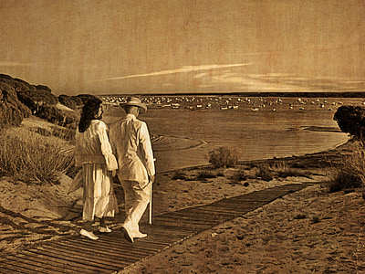 man and woman walking on road near body of water thumbnail