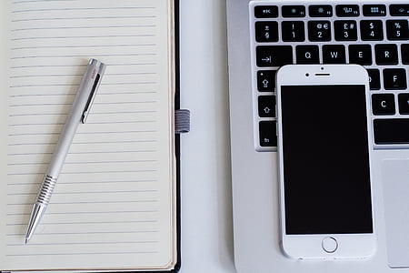 silver iPhone 6 on MacBook Pro and click pen on lined paper thumbnail