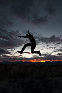 man in mid air over green grass under cloudy sky during sunset thumbnail
