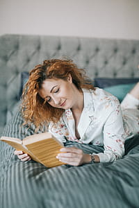 Woman Laying On Bed While Reading Book thumbnail