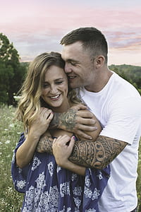 man hugging woman in grass field at daytime thumbnail