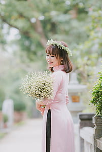 woman in pin dress carrying bouquet of flowers thumbnail