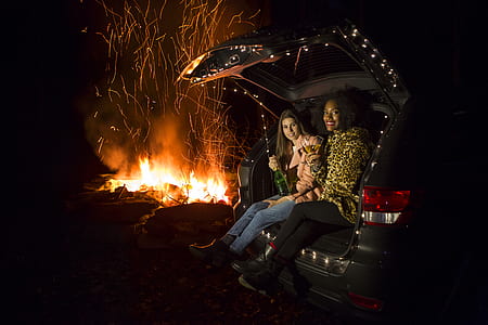 two women sitting on back of the car while watching bonfire thumbnail