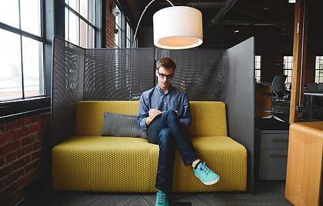 man sitting on yellow sofa under pedestal lamp thumbnail