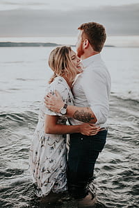 man and woman laughing while standing in water during day thumbnail