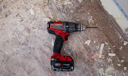 red and black cordless power drill on brown wood surface thumbnail