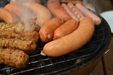 raw sausages on black charcoal grill thumbnail