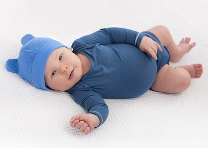 baby wearing blue onesie lying on cushion thumbnail