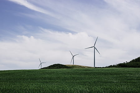 three gray wind turbines on green grass field thumbnail