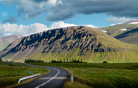 curved road beside grass field during daytime thumbnail