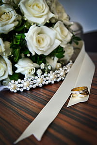 gold-colored clear gemstone encrusted ring on white ribbon near bouquet of white roses thumbnail