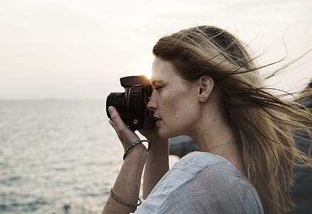 woman taking photograph on body of water at daytime thumbnail