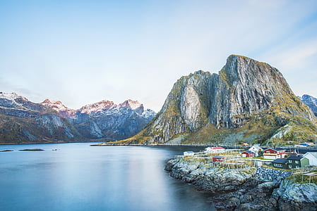 body of water near houses and mountain during daytime thumbnail