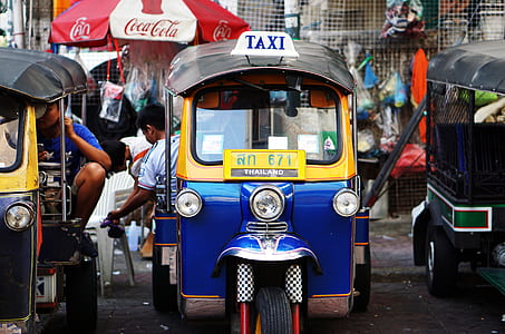 blue and yellow auto rickshaw taxi on parked on black asphalt flooring thumbnail