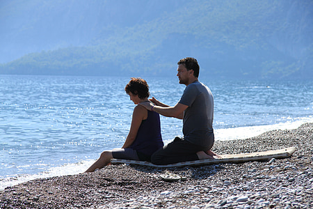 man and woman sitting on shore thumbnail