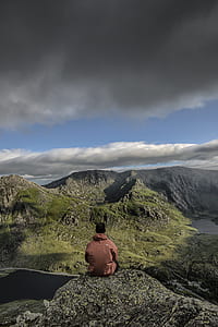 man sitting on mountain edge looking at mountain thumbnail