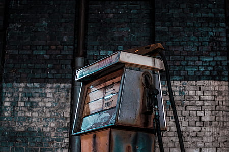 rusted gray, white, and brown Total gasoline pump overlooking gray bricked wall thumbnail