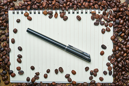 black pen on top of notebook beside cofffee beans thumbnail