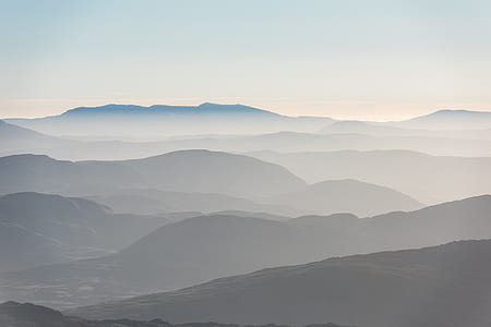 silhouette of mountains with fogs under white sky at daytime thumbnail