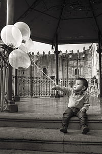 boy sitting on stairs while balloon strapped on his arms thumbnail