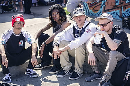 four men sitting on concrete floor during daytime thumbnail