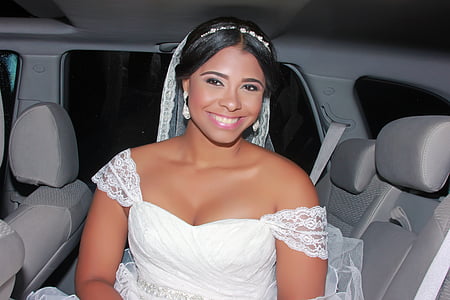 smiling woman wearing white wedding dress and veil inside vehicle thumbnail