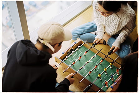 man and woman playing foosball table beside clear glass wall thumbnail