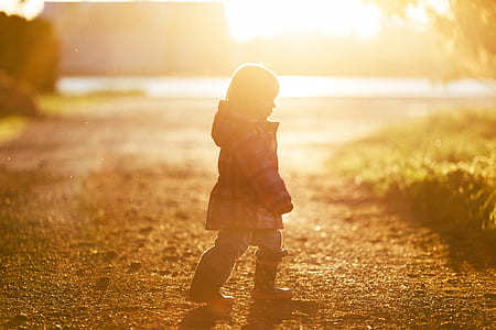 girl walking on ground near grass during sunrise thumbnail