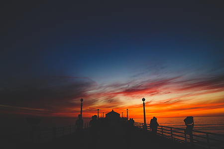 silhouette of people standing on dock during golden hour thumbnail