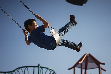 boy swinging during daytime thumbnail
