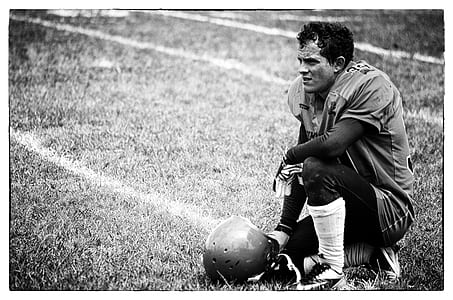 grayscale photo of football player kneeling on grass thumbnail