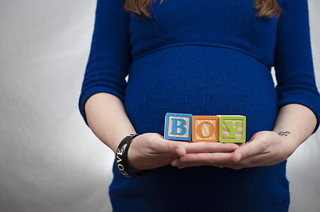 pregnant woman holding a BOY block in front of her tummy thumbnail