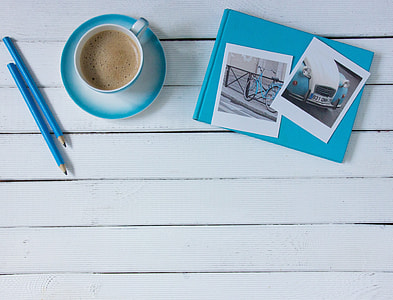 two blue pencils, blue-and-white teacup and saucer set, and blue and white photo album with photos on top thumbnail