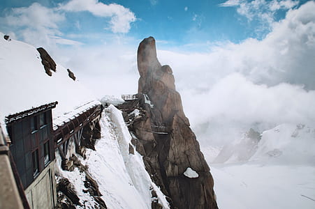 building near cliff under cloudy sky thumbnail