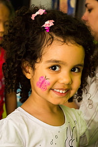 girl wearing white shirt with pink butterfly right cheek face paint thumbnail