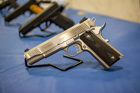 silver and black 45 caliber pistol on top of blue surface thumbnail