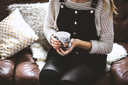 woman sitting on sofa holding cu[ thumbnail