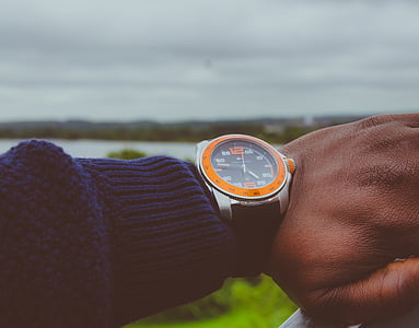 person wearing round orange analog watch thumbnail