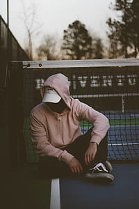 man in pink hoodie sitting near net thumbnail