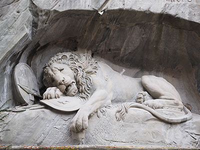 sleeping lion sculpture on stone at daytime thumbnail