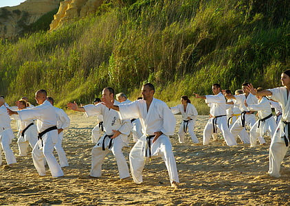 group of people wearing karate gi suit standing on brown sand near green grasses thumbnail