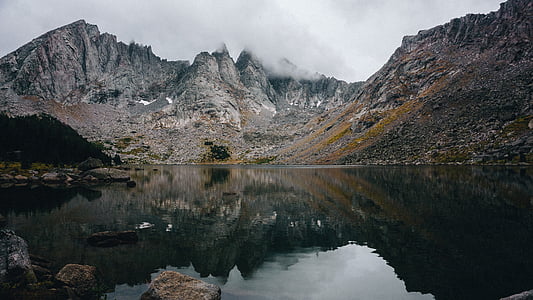 body of water near mountain under white sky thumbnail