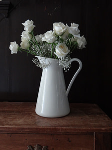 white flowers in white ceramic vase on brown wooden table thumbnail