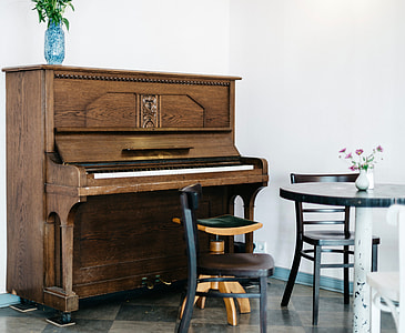 brown upright piano near white painted wall thumbnail
