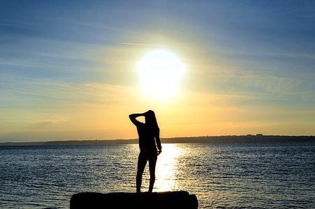 silhouette of woman facing the sea under sunlight thumbnail